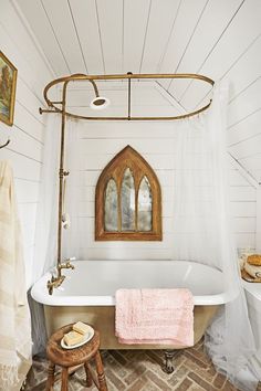 an old fashioned bathtub with a pink towel hanging from it's side in a white bathroom