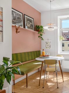 a table with two chairs and a bench in front of a window next to a potted plant