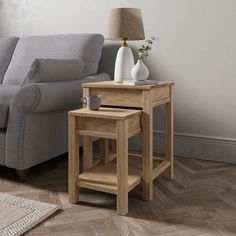 two wooden tables sitting on top of a hard wood floor next to a gray couch