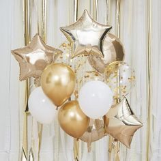 some gold and white balloons are hanging from the ceiling in front of a curtain with stars on it