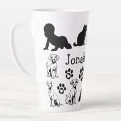 a white coffee cup with black dogs and paw prints on the bottom, along with an image of a dog's name