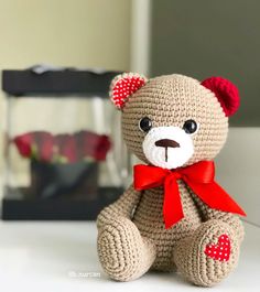 a crocheted teddy bear with a red bow