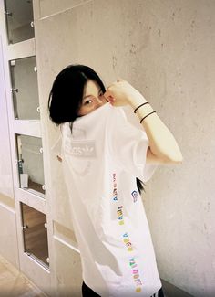 a woman standing in front of a wall holding onto her t - shirt with the word love written on it