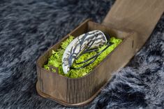 a wooden box filled with green plants on top of a fur covered floor