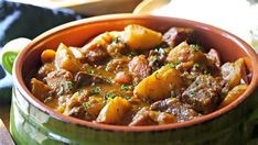 a green bowl filled with stew on top of a table