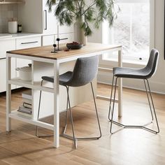 two chairs sitting at a kitchen table in front of a potted plant on the counter