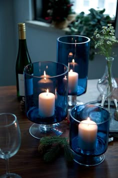 candles are lit in glass vases on a table