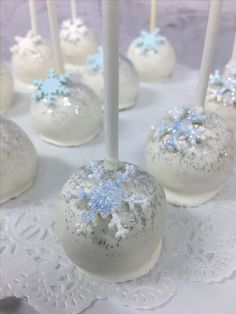 white cake pops with blue snowflakes on them and some candles in the middle