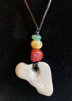 This necklace is made with an Africa-shaped hag stone collected at the Oregon coast, a red coral bead, a yellow glass bead and green aventurine strung on nylon silky cord. It is adjustable from 14 to 26 inches, and has a 3 1/4 inch drop. Heart-shaped Adjustable Necklace With Natural Stones, Heart-shaped Necklace With Natural Stones, Adjustable Heart-shaped Natural Stone Necklace, Adjustable Heart Pendant Beaded Necklace As Gift, Casual Necklace With Natural Stones As Gift, Casual Necklace With Natural Stones For Gift, Adjustable Heart-shaped Gemstone Bead Necklace, Casual Adjustable Necklace With Heart Beads, Casual Adjustable Heart Beads Necklace