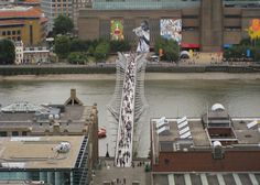 a group of people walking across a pedestrian bridge over a body of water in the city