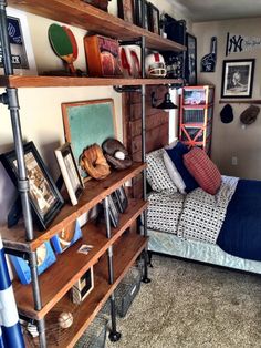 a bed room with a neatly made bed and lots of shelves on the wall next to it