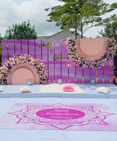 a couple of pink chairs sitting on top of a purple and white table covered in flowers