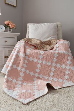 a pink and white blanket sitting on top of a bed