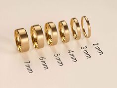 four different sizes of wedding rings sitting on top of a piece of paper next to each other