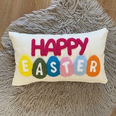 an embroidered pillow with the words happy easter on it, sitting on a fluffy rug