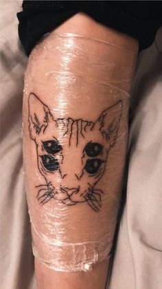 a cat tattoo on the leg of a person's leg, which is covered in tape