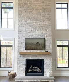 a living room filled with furniture and a fire place in front of two large windows