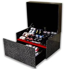 an open shoe box with many pairs of shoes in the bottom drawer and one pair of sneakers on top