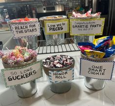 three buckets filled with different types of candies sitting on top of a counter