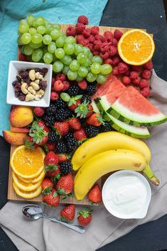 various fruits and vegetables are arranged on a white surface, including watermelon, grapes, peaches, strawberries, blueberries, raspberries