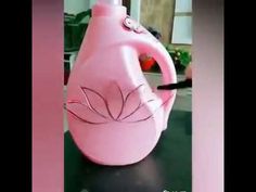 a pink jug with a flower painted on it sitting on top of a black table