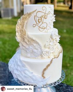 a three tiered wedding cake decorated with feathers