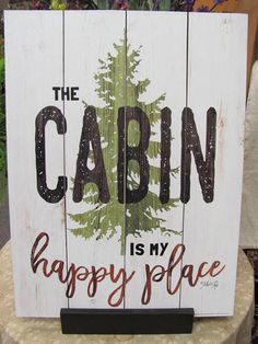 a wooden sign that says the cabin is my happy place on top of a table