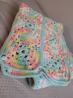 a crocheted blanket is laying on a bed