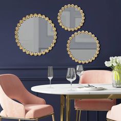 a dining room table with two chairs and three mirrors on the wall