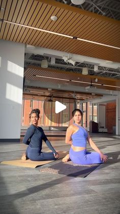 two women sitting on yoga mats in an empty room