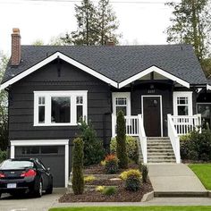 a black and white house with two cars parked in front of the garage door on the driveway