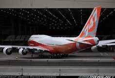 an orange and white airplane is on the tarmac with people standing near by it