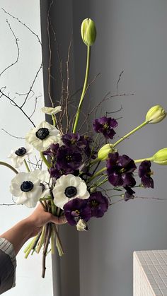 a person holding a bouquet of flowers in their hand with purple and white flowers on it