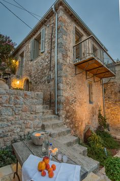 an outdoor table with fruit on it in front of a stone building at night time