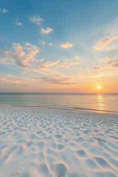 the sun is setting over the beach with white sand