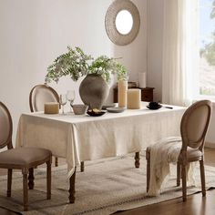 a dining room table with chairs and a vase on top of it, next to a window