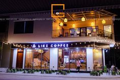 the front of a coffee shop lit up at night with people standing outside and eating