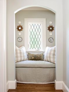 a window seat in the corner of a room with two pillows on top of it