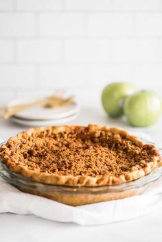 the best dutch apple pie is in a glass pie dish on a white countertop