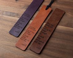 two bookmarks with words on them sitting on a wooden table next to each other