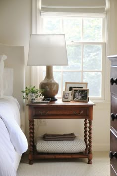 a bed room with a neatly made bed and a lamp on a table next to it