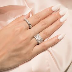 a woman's hand with two wedding rings on her left and the other hand wearing a pink dress