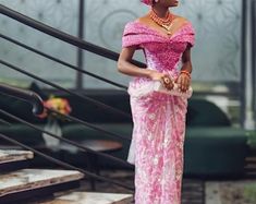 a woman in a pink dress is standing on some steps and looking off to the side