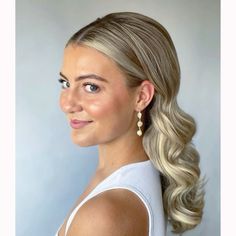 a woman with blonde hair and earrings on her head, wearing a white tank top