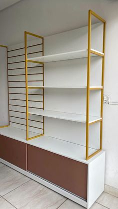 an empty white and brown shelf with gold bars on it's sides in a room