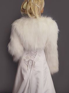 a woman in a white wedding dress and fur coat on the back of her head