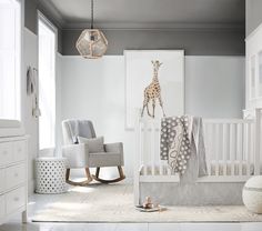 a baby's room with a giraffe on the wall and rocking chair