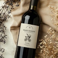 a bottle of wine sitting on top of a table next to dried flowers and branches