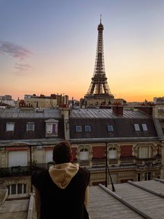 the eiffel tower is in the distance, with a woman looking at it