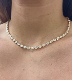 When the occasion calls for a grand entrance, this necklace is here for every milestone. Handcrafted in 14k solid gold featuring 49 diamonds, with an average total carat weight of 6.90cts that are bezel set to create a continuous stream of shine. Available in 14k Yellow Gold, White Gold, and Rose Gold Diamond Total Carat Weight: approximately 6.90cts Available in Oval, Princess, Marquise and Pear cuts Diamond Color: F-G Diamond Clarity: VS1 Diamonds appear halfway around the neckline. Made to or Diamond Teardrop Jewelry With Bezel Setting, Teardrop Diamond Jewelry With Bezel Setting, Anniversary Drop Necklace With Bezel Setting, Anniversary Drop Necklaces With Bezel Setting, Luxury Pear Shaped Necklace With Single Cut Diamonds, Luxury Pear-shaped Necklace With Single Cut Diamonds, Luxury Pear-shaped Single Cut Diamond Necklaces, Luxury Pear Shaped Single Cut Diamond Necklace, Luxury Pear-shaped Single Cut Diamond Necklace